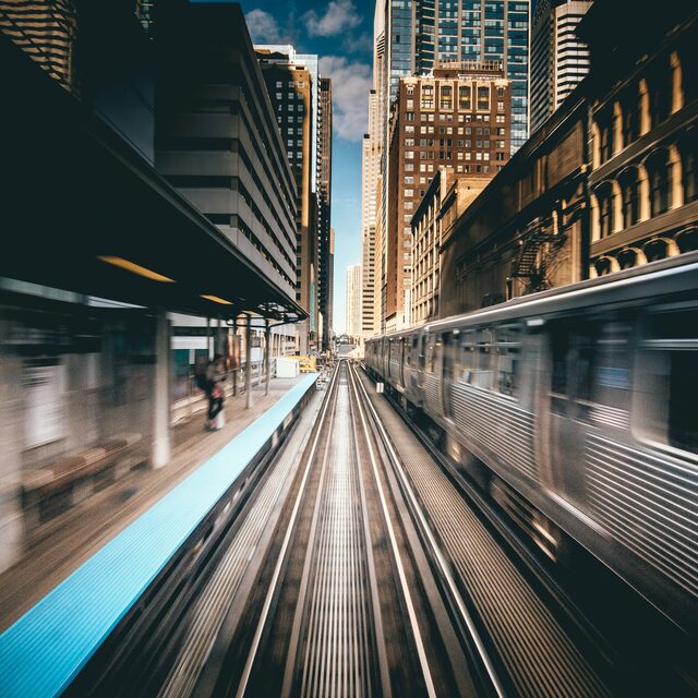 Elevated commuter rail tracks running between downtown high-rises, shot in motion